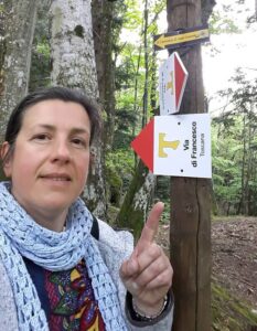 A female hiker points to signs on the St. Francis Way